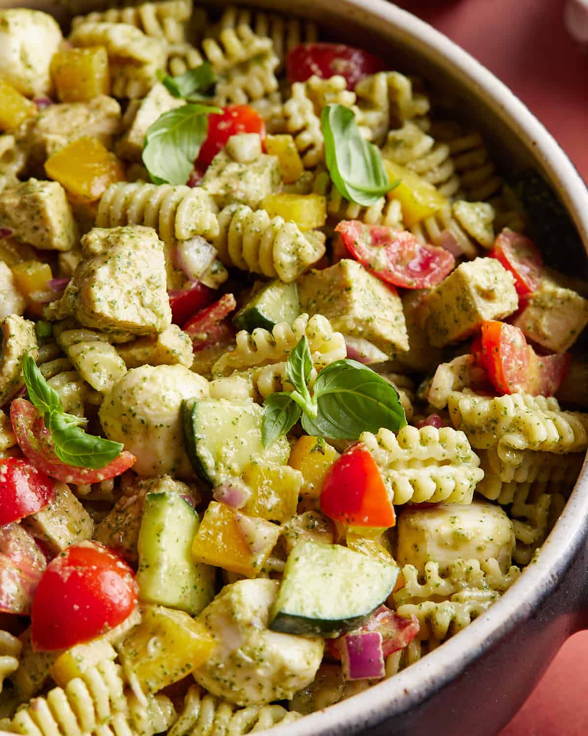 Overhead up close image of chicken pesto pasta salad with garnish. 
