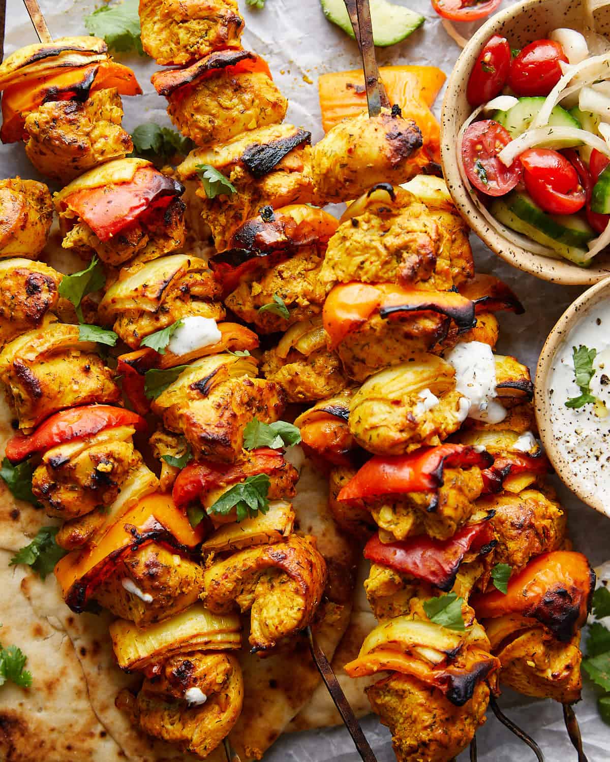 Up close image of chicken kabobs in the oven with garnish. 