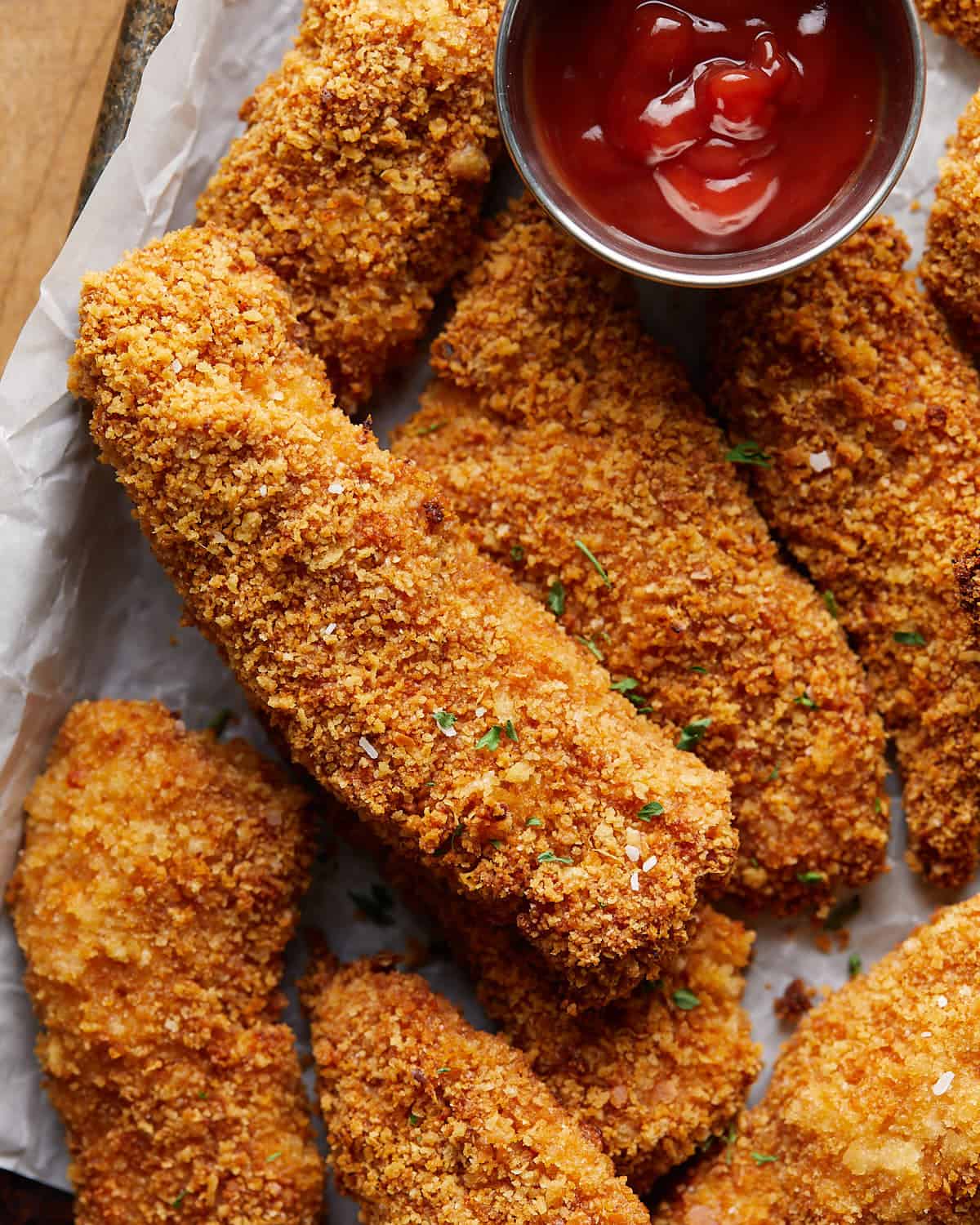 Up close overhead image of crispy chicken tender with garnish. 