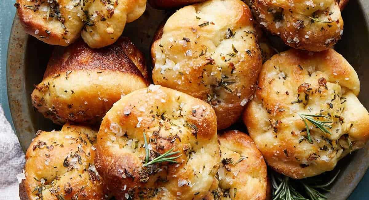 Up close overhead image of garlic rosemary focaccia muffins with garnish. 