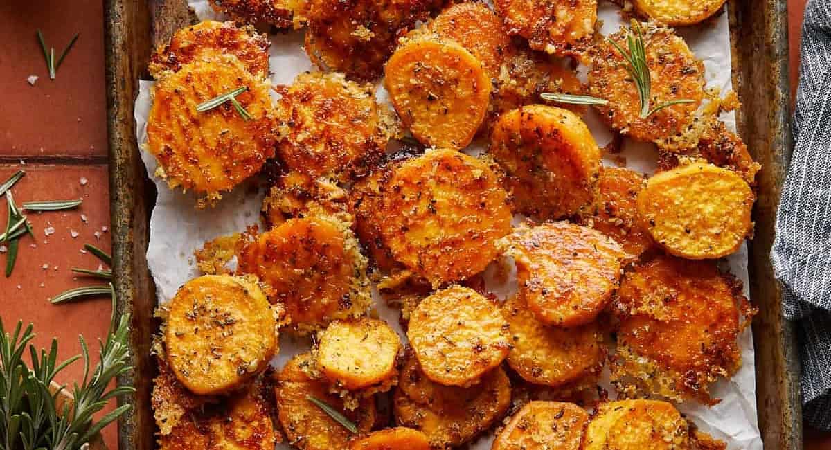 Overhead image of savory roasted sweet potatoes with parmesan and herbs on baking dish. 