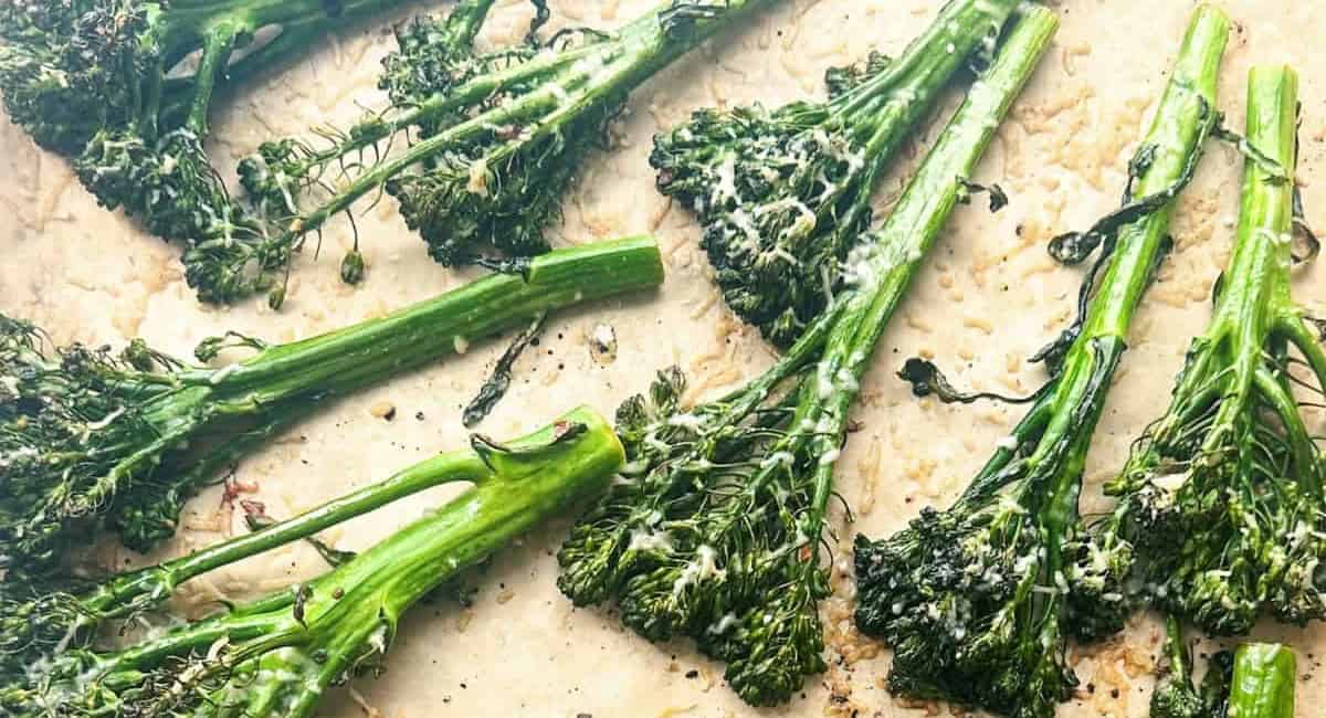 Overhead image of charred broccolini on parchment paper. 