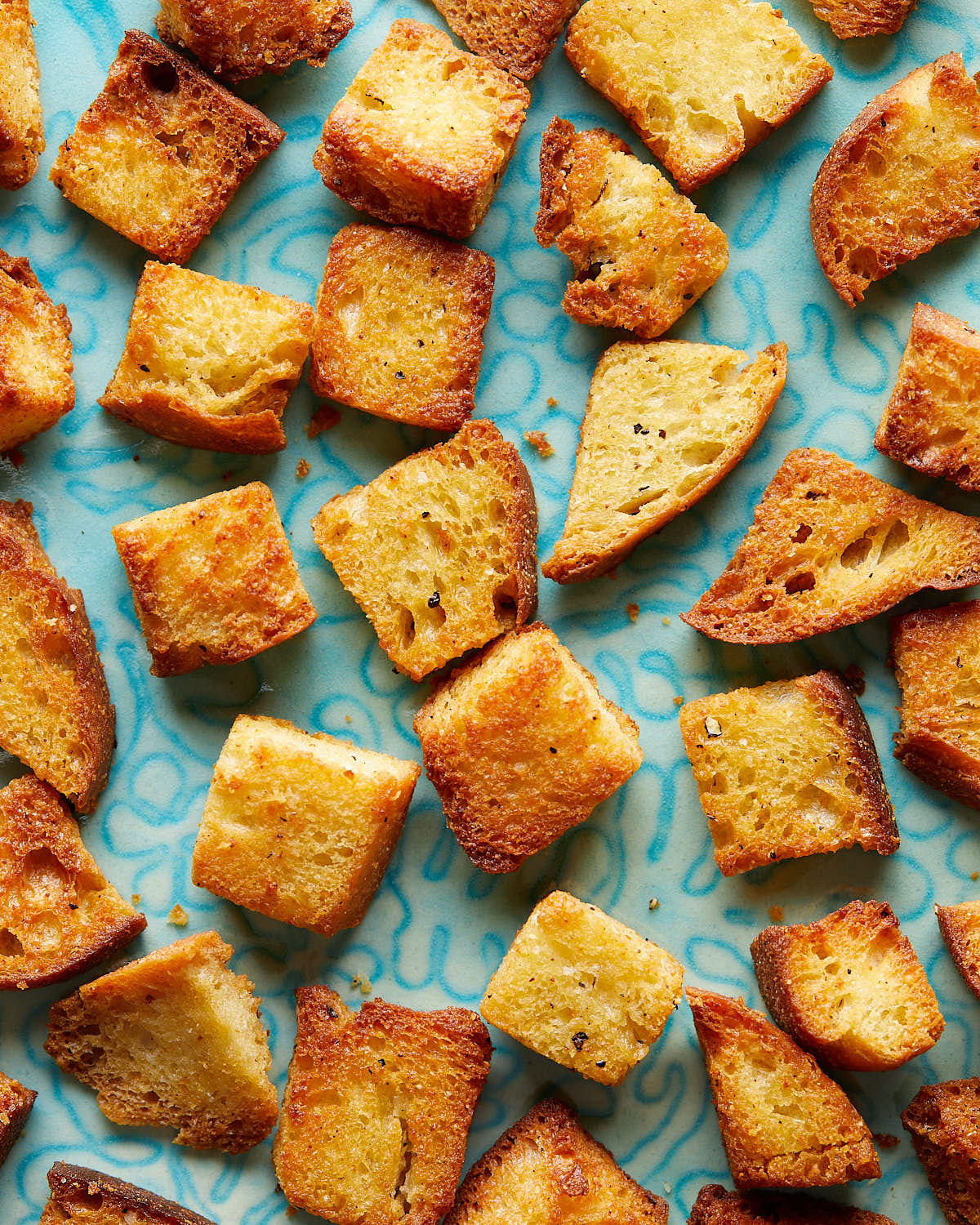Overhead up close image of air fryer croutons on white dish. 