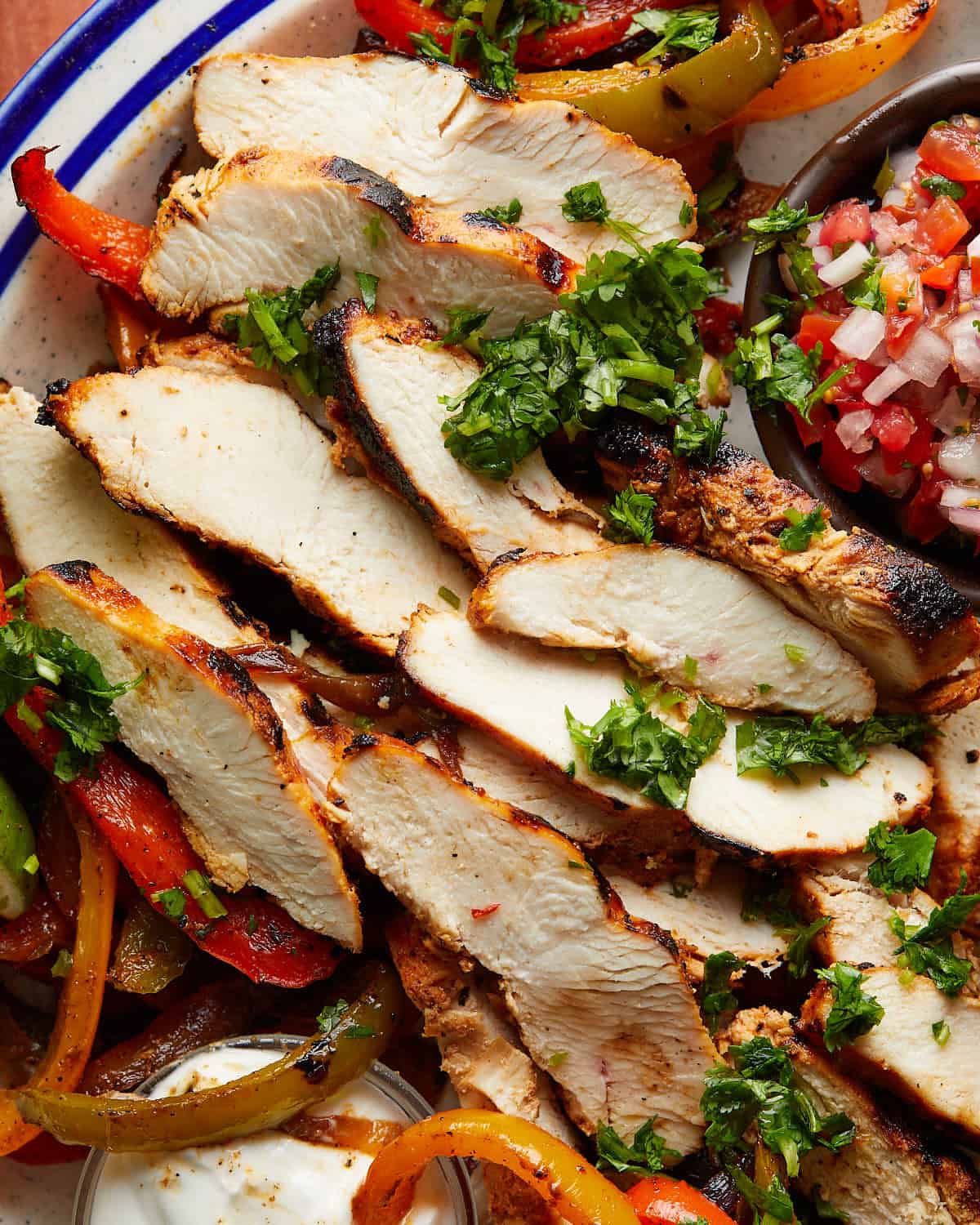 Overhead up close image of grilled chicken fajitas with garnish. 