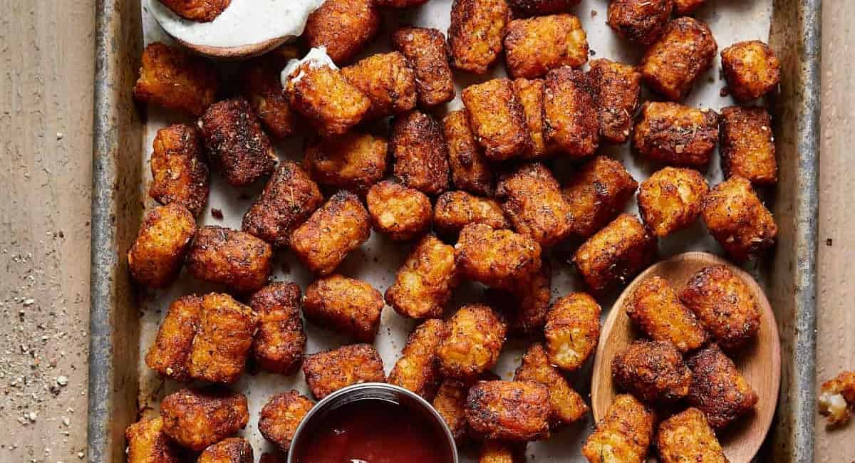 Overhead image of seasoned tater tots on baking sheet. 