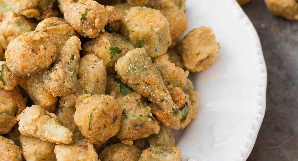 Up close image of southern fried okra with cornmeal on a white dish. 