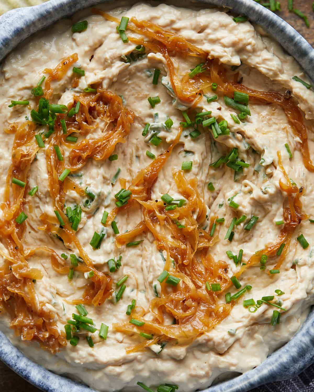 Up close overhead image of homemade caramelized french onion dip with garnish. 
