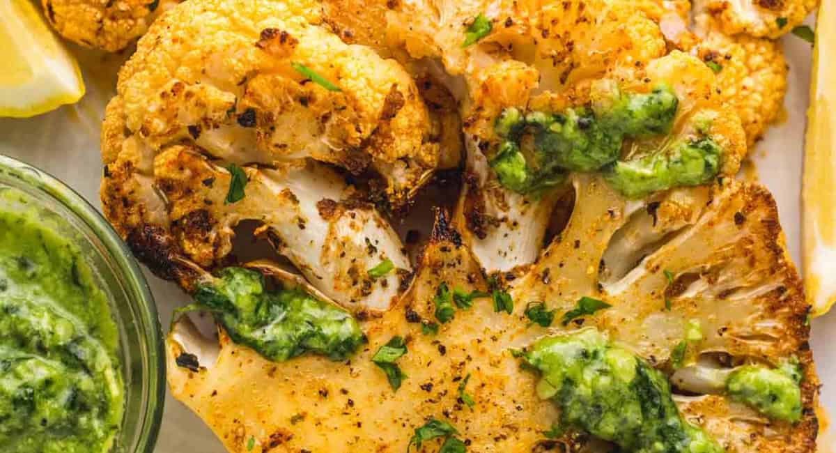 Overhead image of roasted cauliflower steaks with garish sauce. 