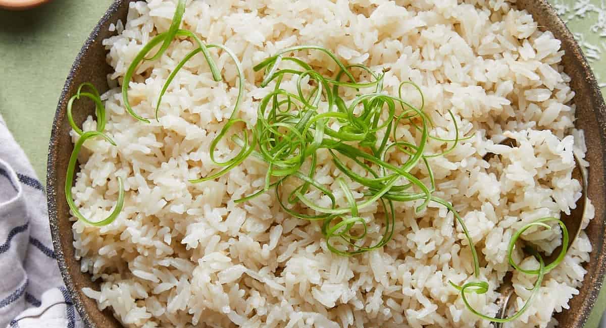 Overhead image of coconut jasmine rice with garnish in brown bowl. 