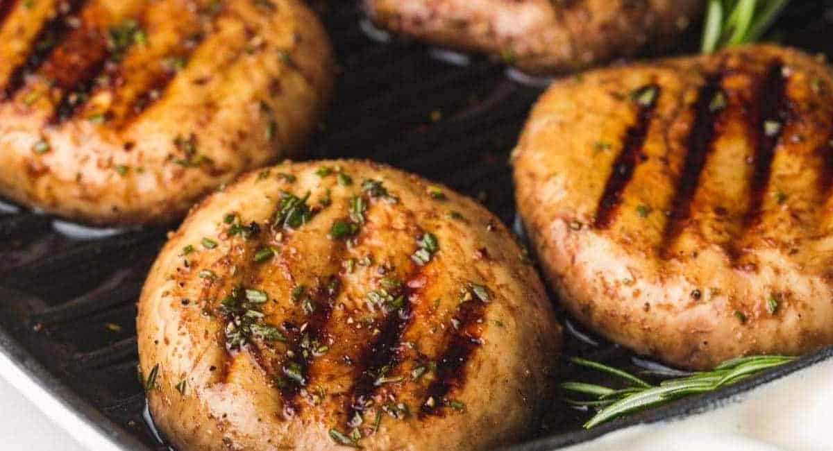 Overhead up close image of grilled portobello mushrooms with garnish. 