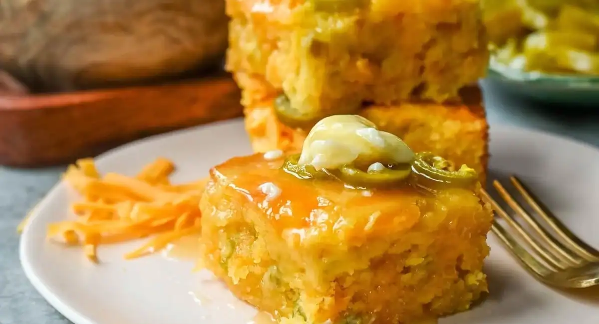 Side profile image of jalapeno cheddar cornbread on white plate with fork. 