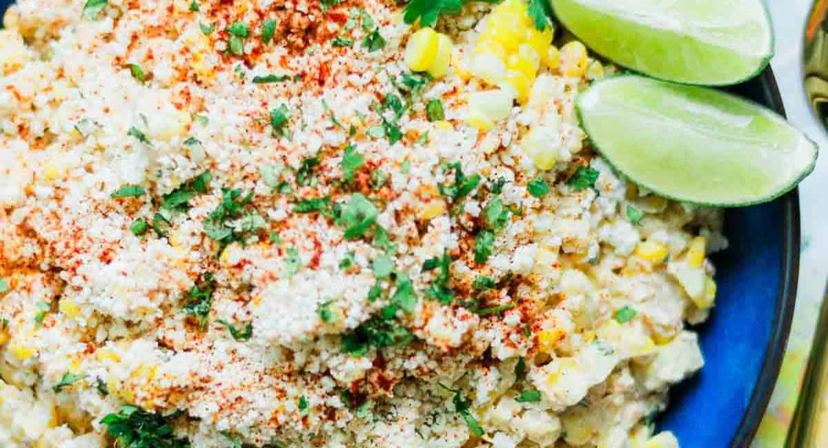 Overhead image of Mexican-style elote salad with garnish and lime. 