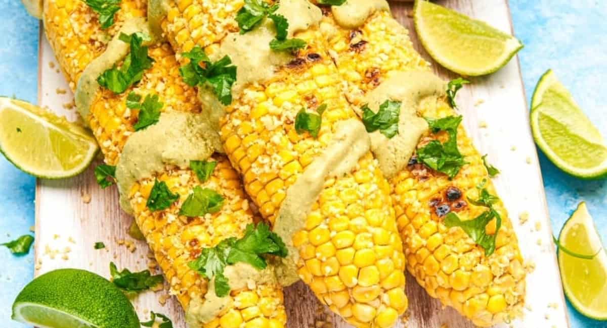 Overhead image of mesquite-grilled corn in the husk with garnish. 