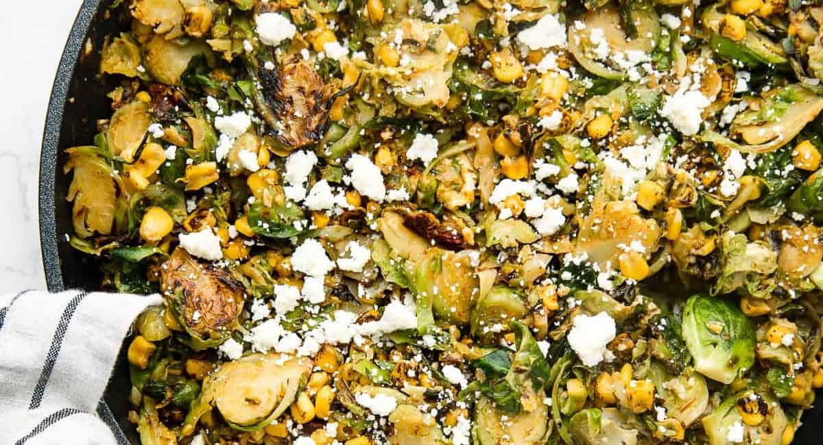 Overhead and up close image of Mexican chipotle brussel sprouts with garnish. 