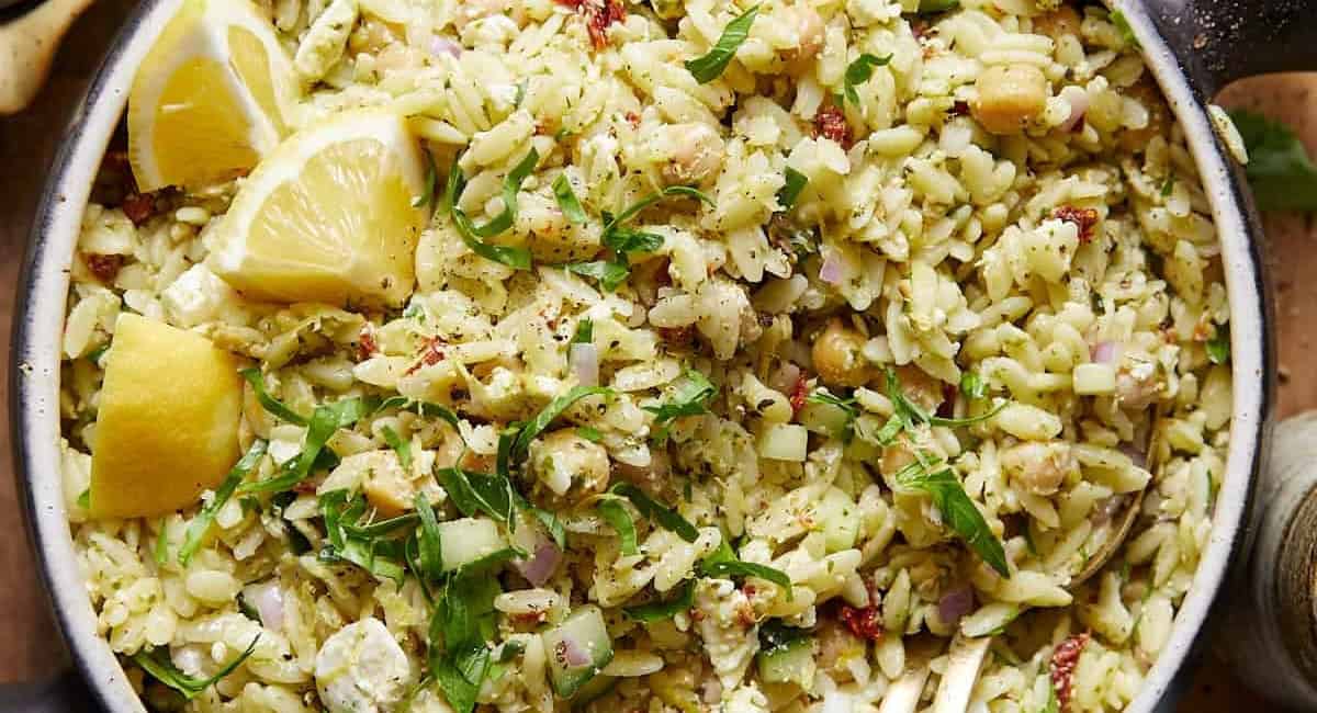 Overhead up close image of easy pesto orzo salad with garnish in bowl. 