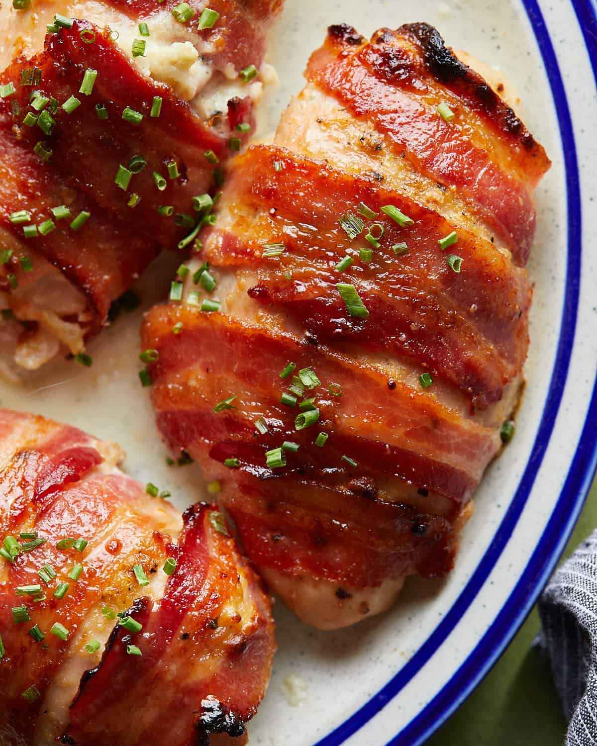 Up close overhead image of bacon wrapped chicken breasts with garnish.