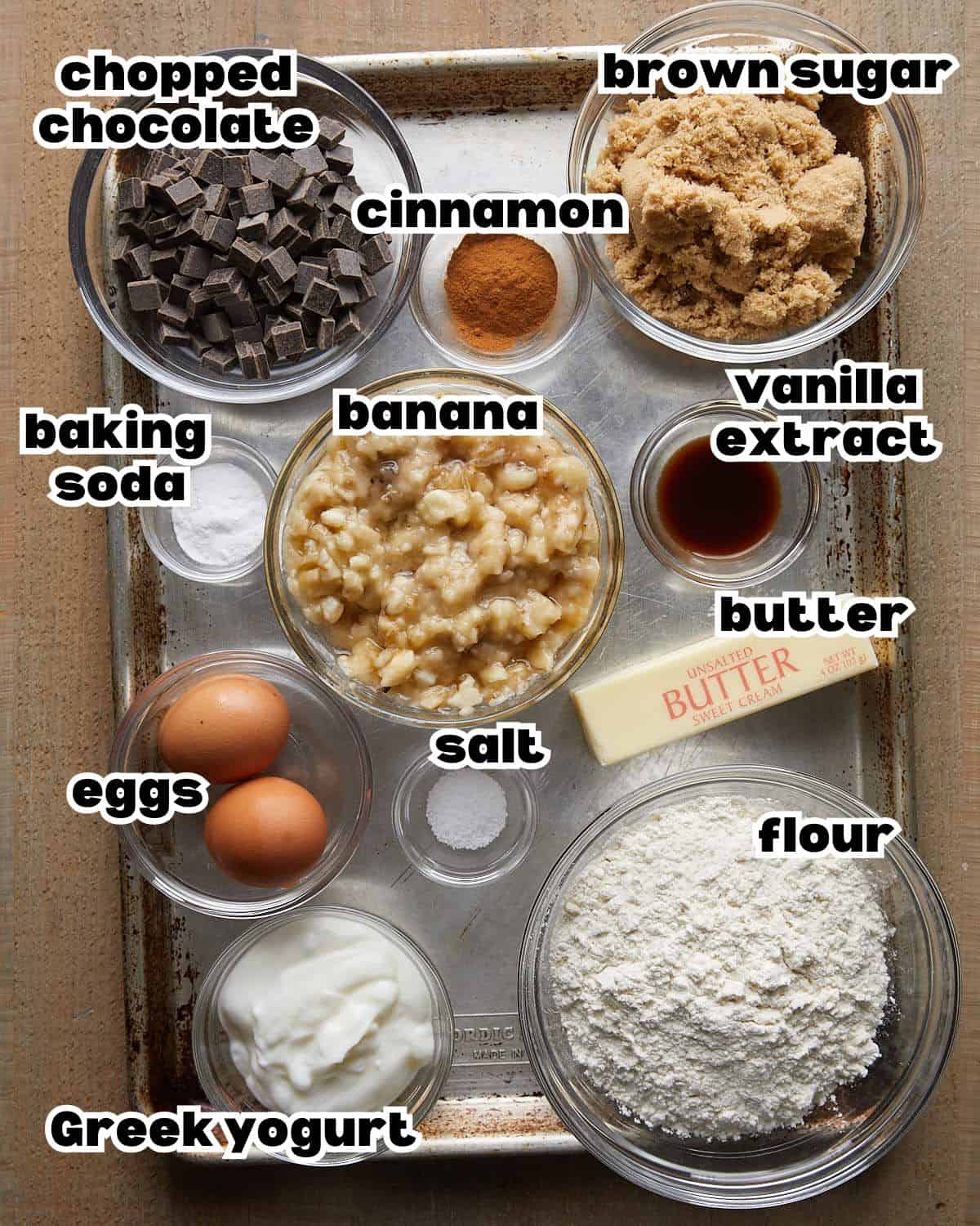 Overhead image of ingredients needed to make chocolate chunk banana bread on baking sheet.