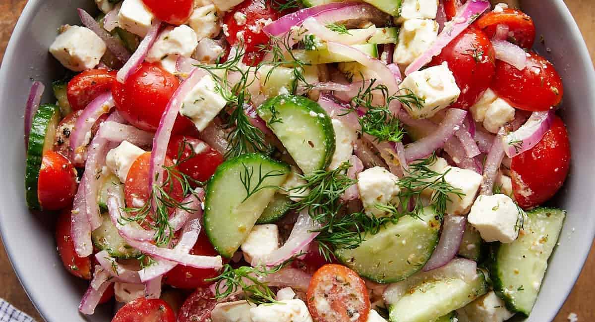 Overhead image of cucumber tomato and feta salad with garnish. 