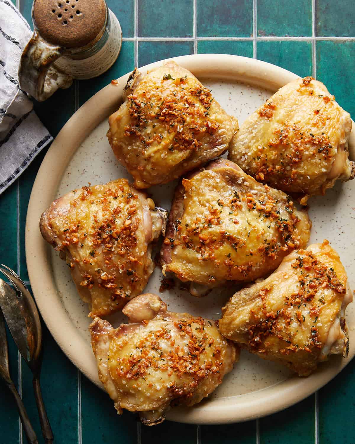 Overhead image of garlic butter chicken thighs on a plate, coated in rich garlic butter sauce with golden-brown skin and fresh herbs, ready to serve.