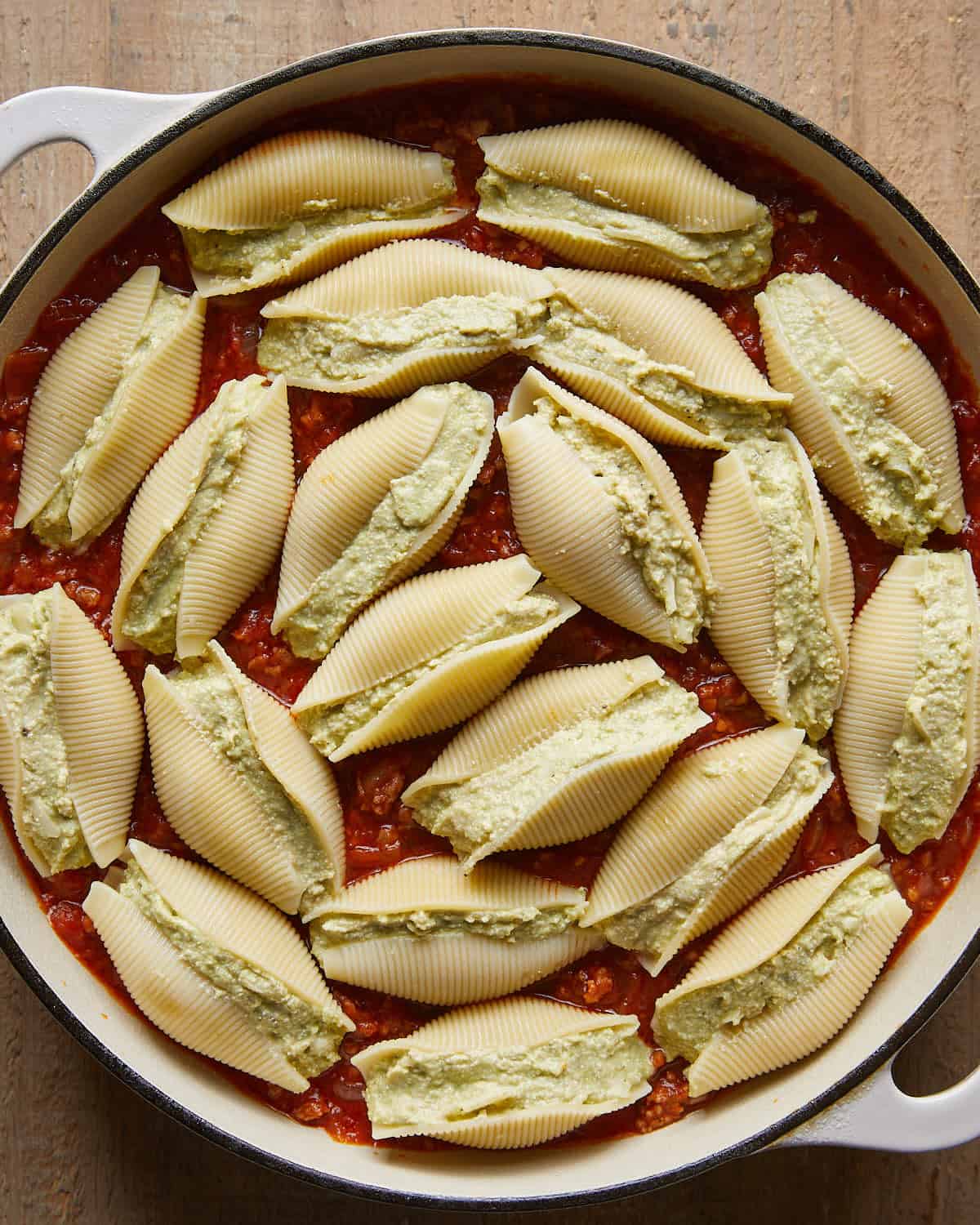 Stuffed shells nestled into meat marinara sauce in a baking dish for baked stuffed shells.