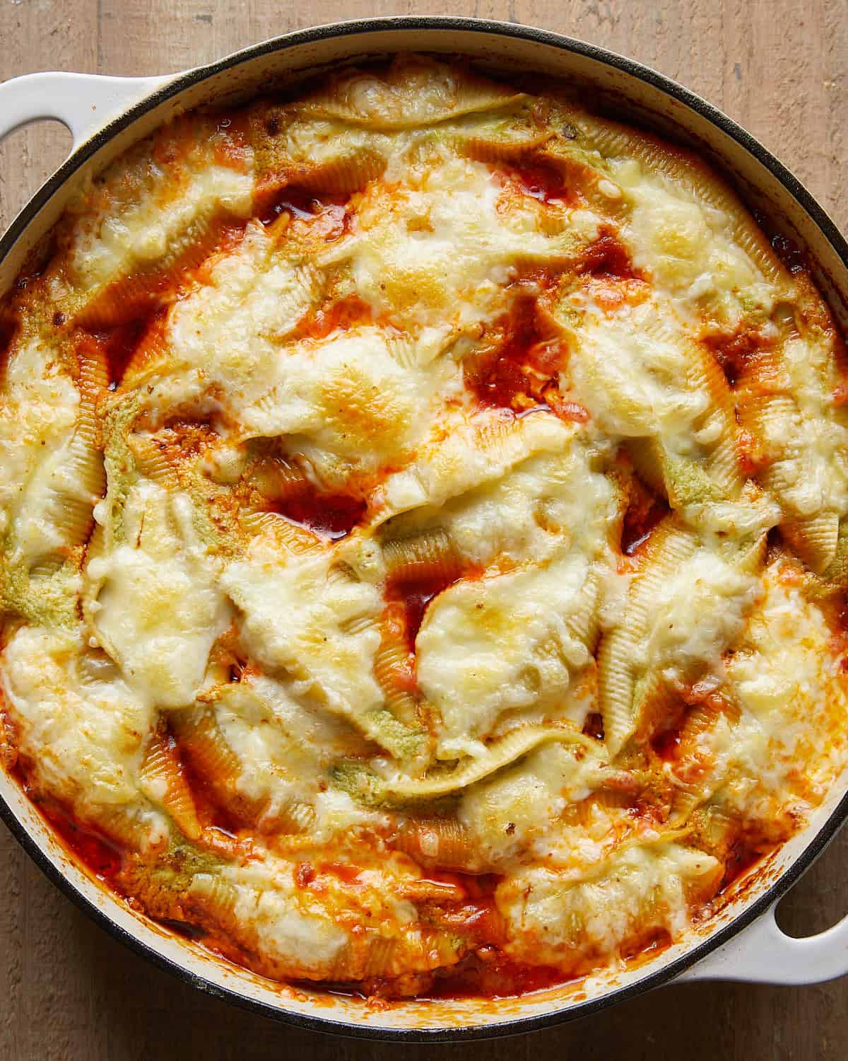 Overhead view of baked stuffed shells fresh from the oven, cheesy and golden in a white baking dish