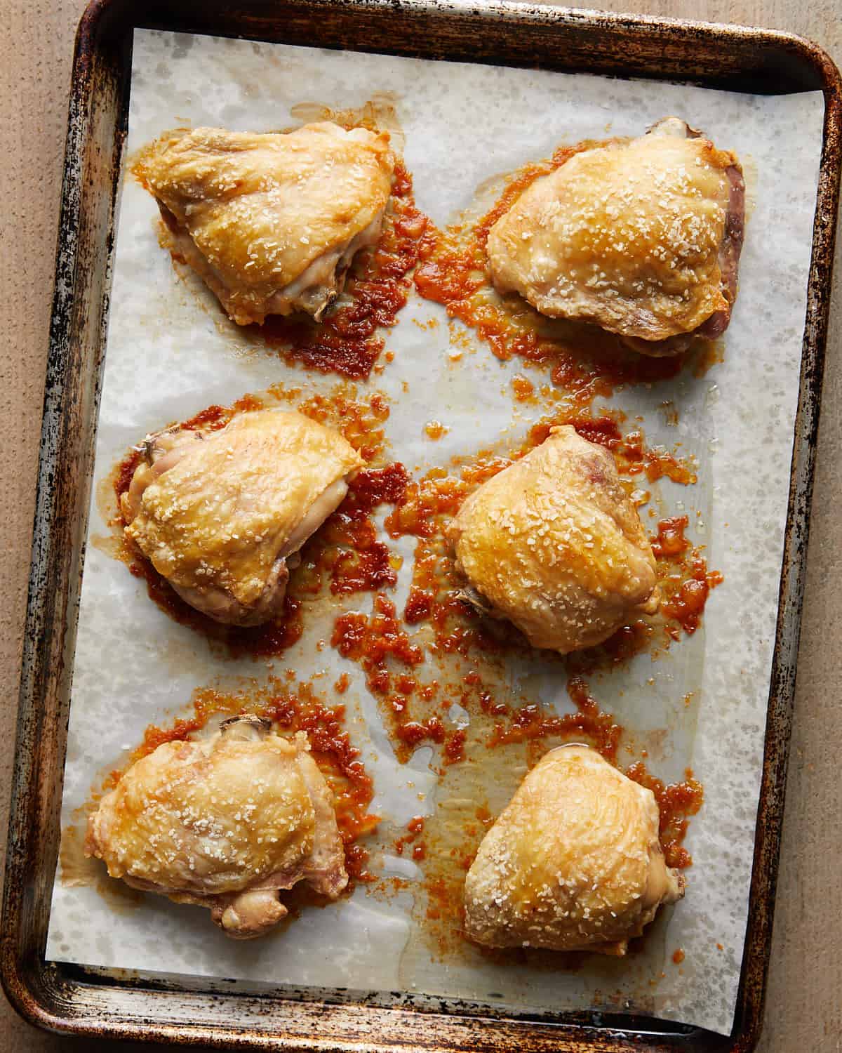 Overhead photo of baked chicken thighs fresh from the oven, golden brown and juicy with crisped skin, resting in the pan and ready to serve.