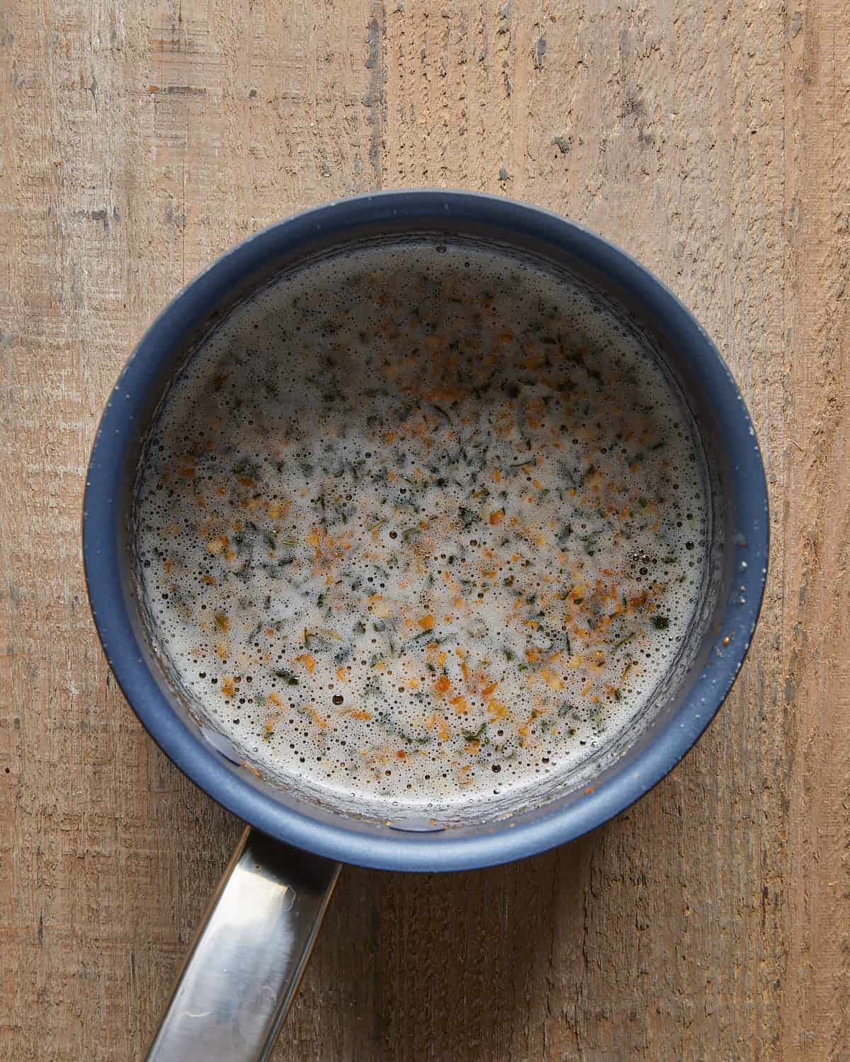 Overhead view of garlic butter for chicken thighs, featuring melted butter mixed with fresh minced garlic and seasonings in a small pot, ready to brush over the chicken.