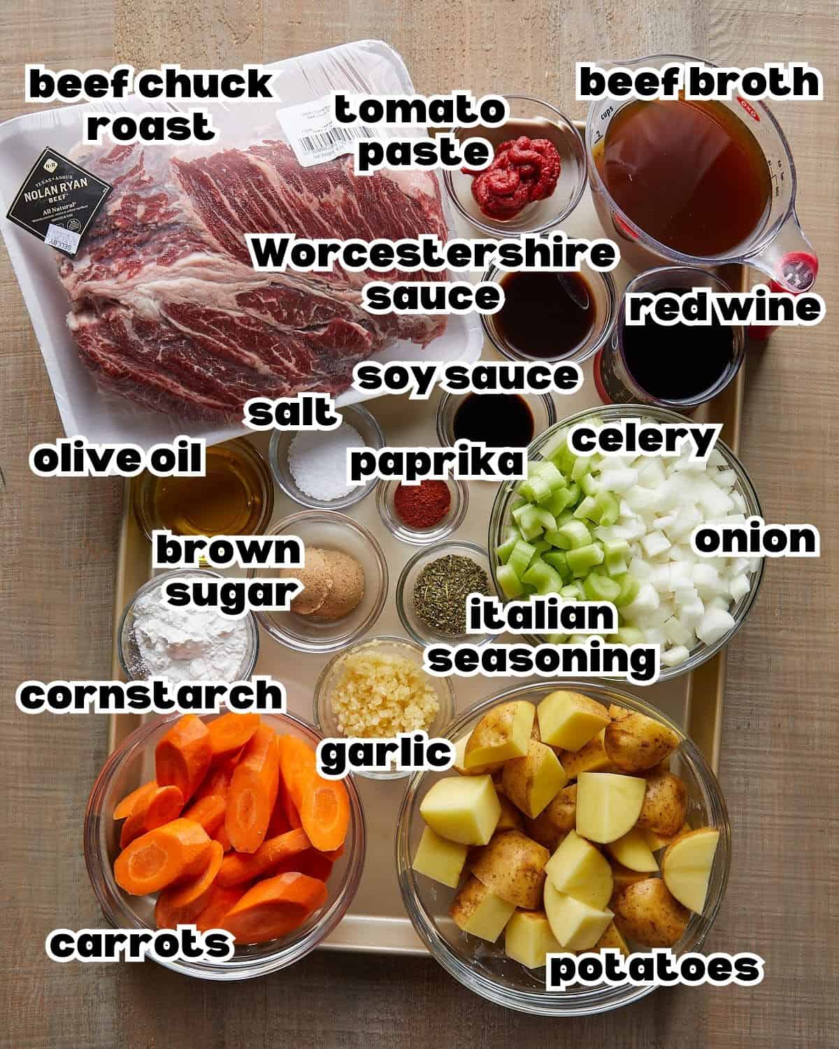 Overhead view of ingredients for Dutch Oven Pot Roast, including beef chuck roast, potatoes, carrots, onions, and herbs.