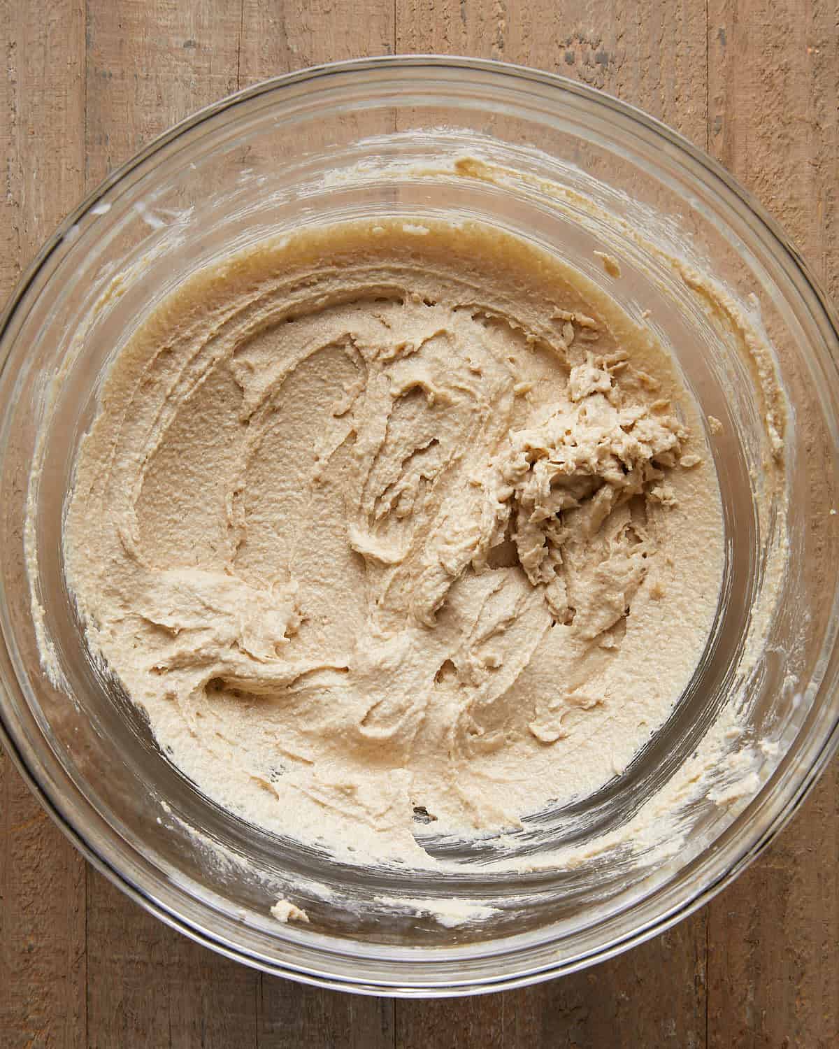 Overhead image of beating sugars for no chill chocolate chip cookies, showing brown and white sugar being mixed until smooth and glossy for a chewy cookie dough base.