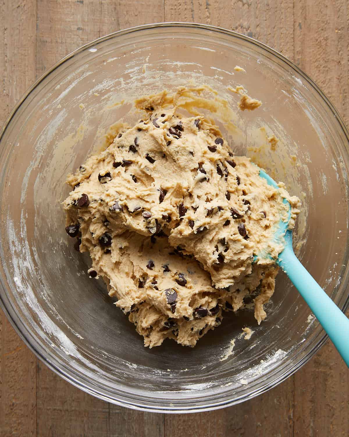 Overhead image of flour and chocolate chips being added to the dough for no chill chocolate chip cookies, showing the final mixing step before baking.