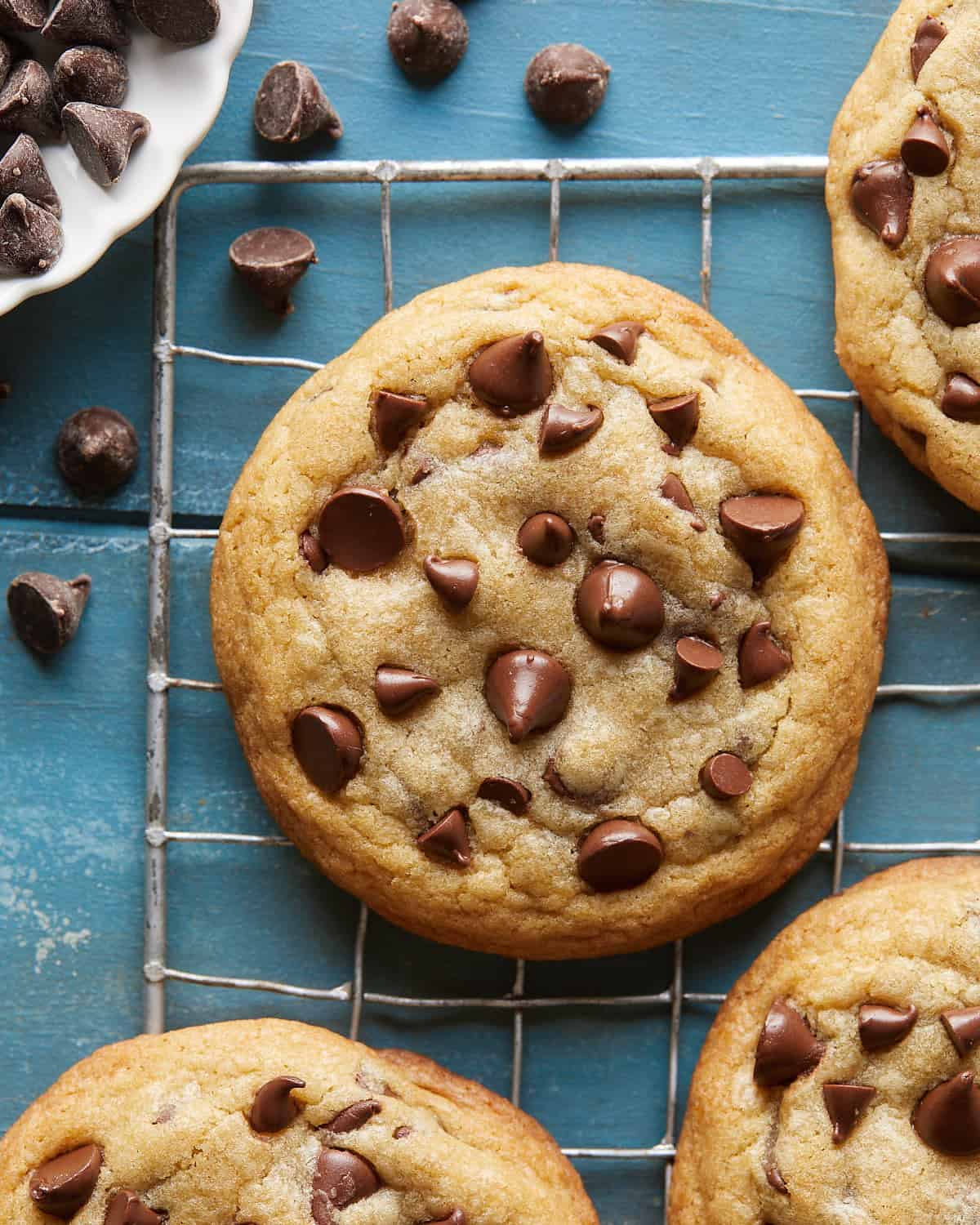 Up-close overhead image of a no chill chocolate chip cookie on a wire rack, showing crisp golden edges, soft chewy center, and melted chocolate chips.