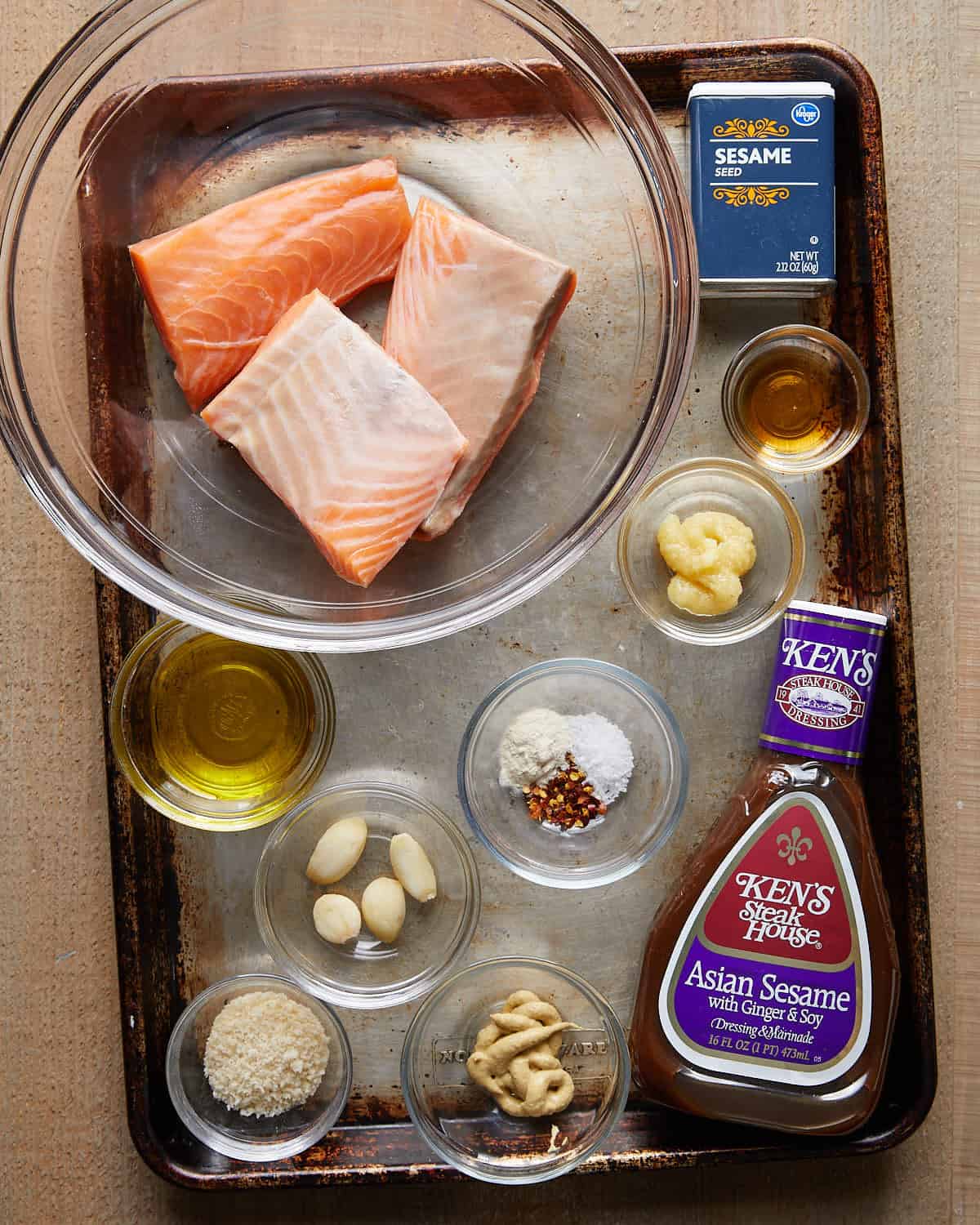 Overhead shot of ingredients for Asian salmon burgers, including fresh salmon, green onions, garlic, ginger, soy sauce, sesame oil, breadcrumbs, and eggs.