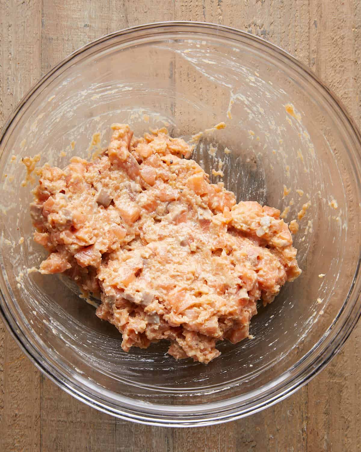 Overhead image of chopped salmon pieces mixed with salmon paste, showing a chunky, well-combined mixture ready to shape into patties for Asian salmon burgers.