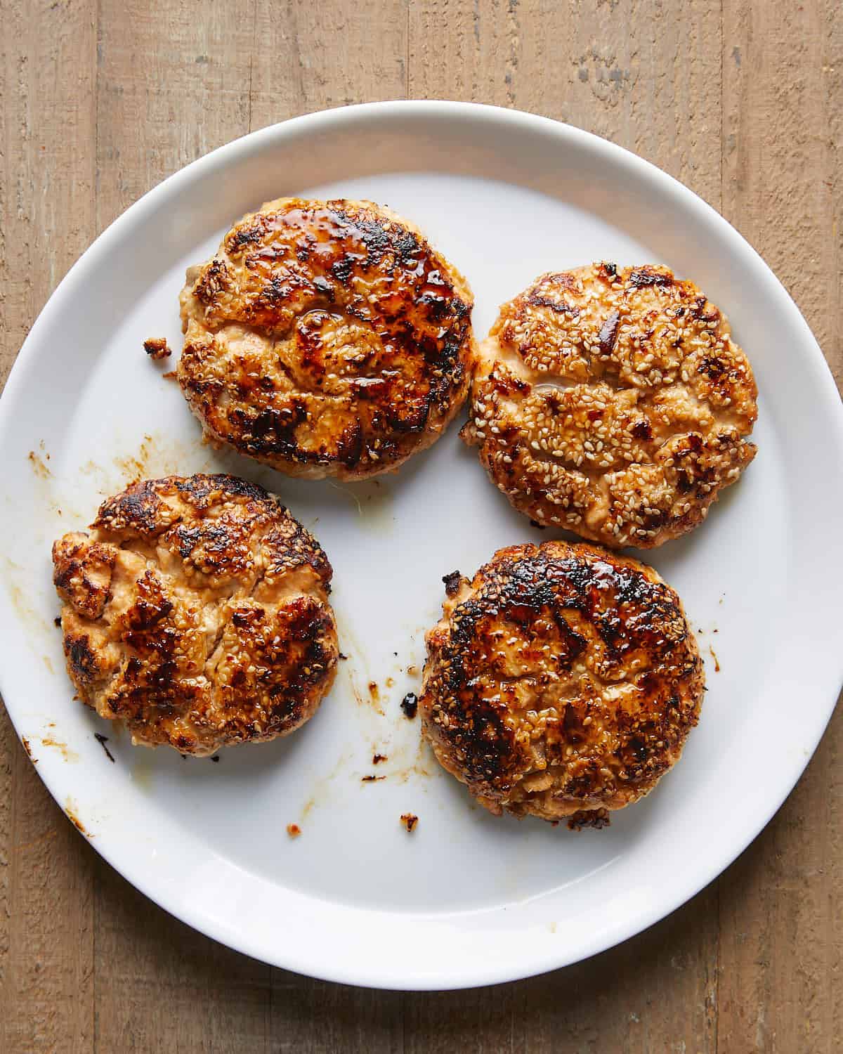 Overhead image of perfectly cooked and seared Asian salmon burgers with crispy edges and tender centers.