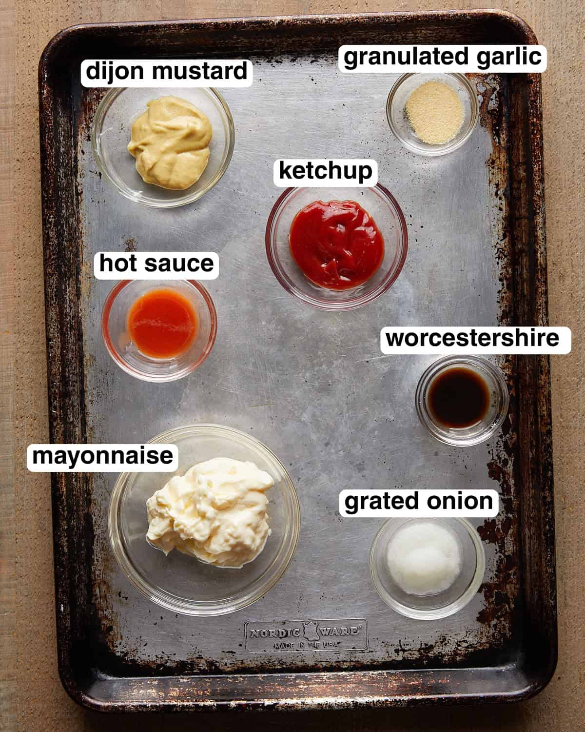 Labeled burger sauce ingredients arranged on a sheet pan.