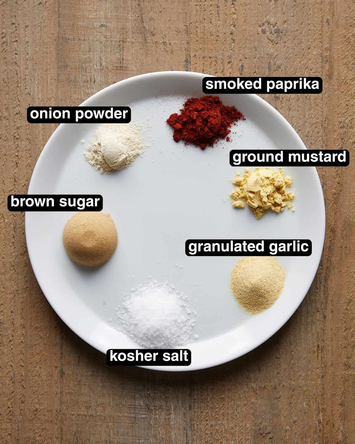 Overhead photo of spices arranged on a small white plate for homemade burger seasoning.