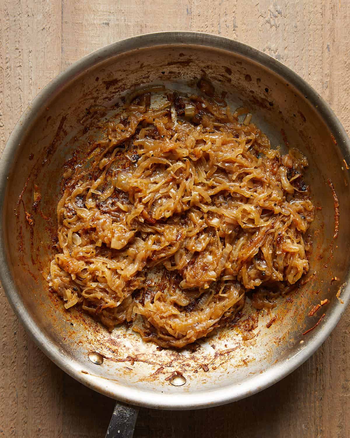 Sliced onions turning golden brown as they caramelize in a pan.