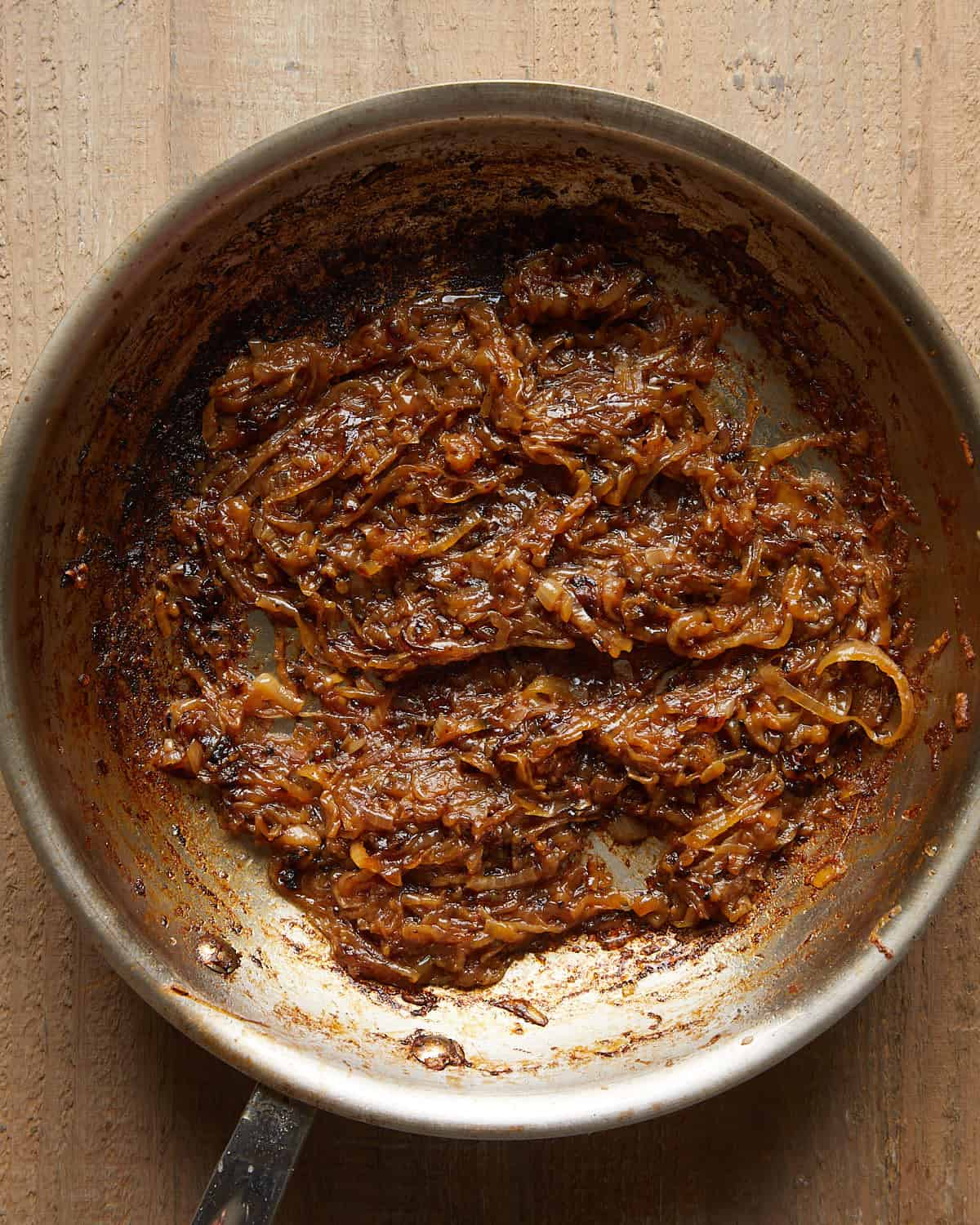 Deep golden caramelized onions cooking down in a pan.