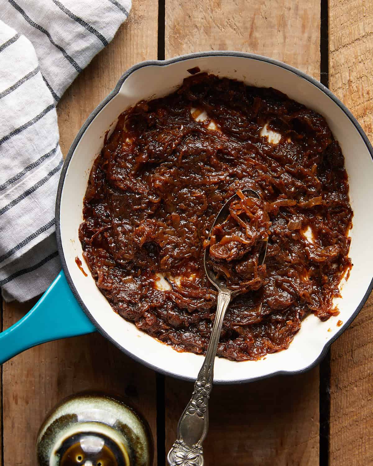 Pan of finished caramelized onions with a spoon resting in the center.
