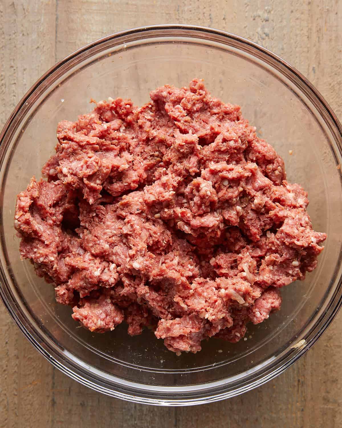 Ground beef mixture in a glass bowl before shaping into burger patties.