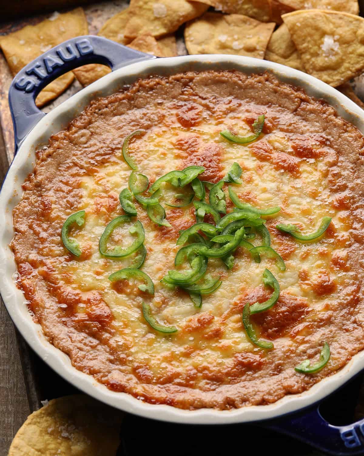 Close up of baked cheesy bean dip topped with melted cheese and sliced jalapeños.