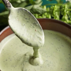 Close-up of creamy basil aioli being spooned from a small bowl.
