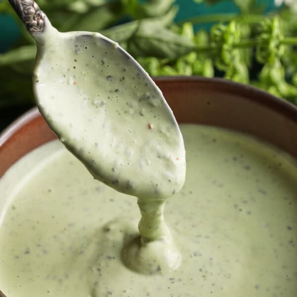 Close-up of creamy basil aioli being spooned from a small bowl.
