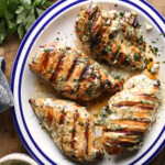 Overhead photo of grilled Caesar chicken breasts topped with herbs and served with Caesar sauce.