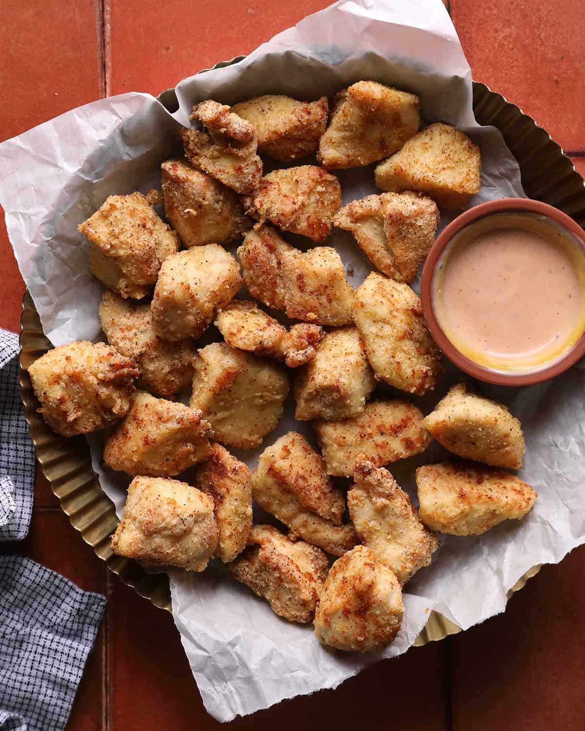 Air fryer chicken bites served in a basket with dipping sauce.