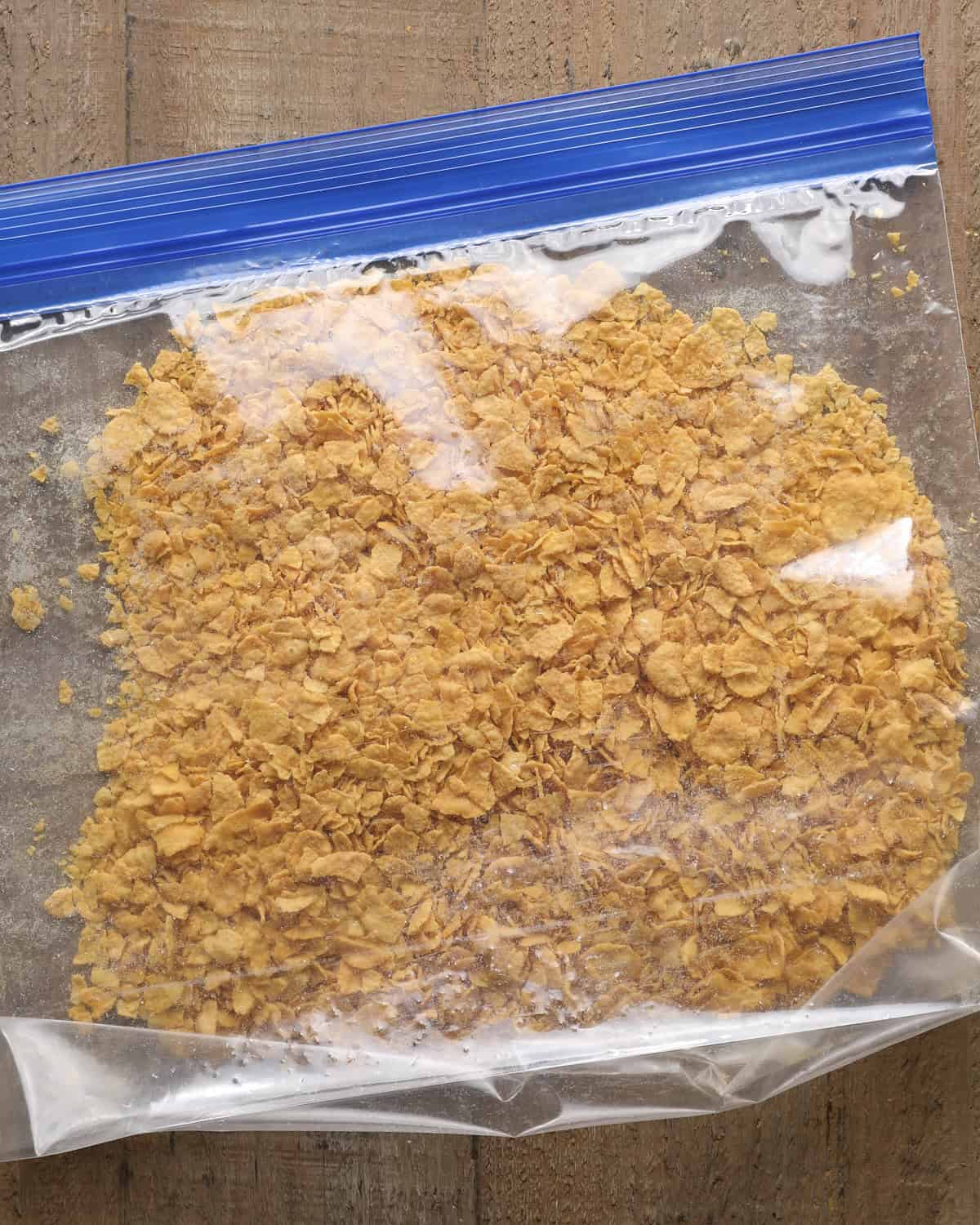 Cornflakes crushed into coarse crumbs in a zip-top bag.