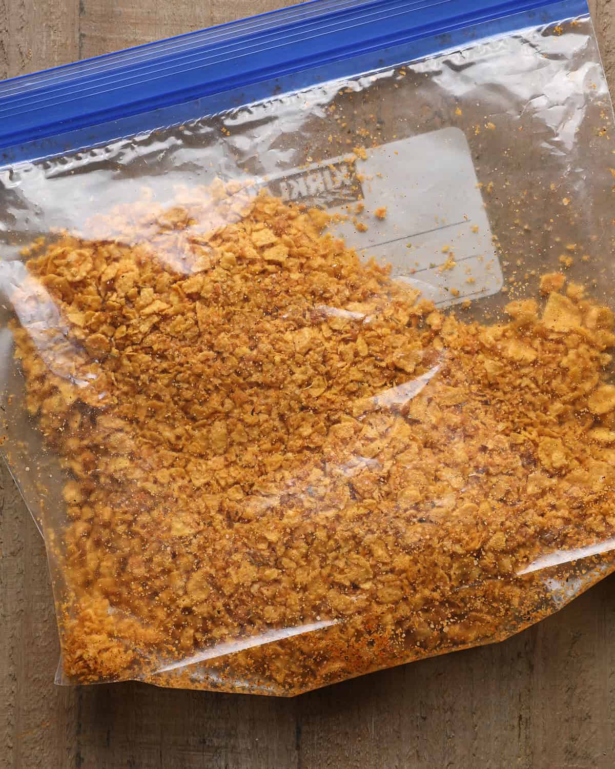 Crushed cornflakes mixed with Parmesan and seasonings in a zip-top bag.