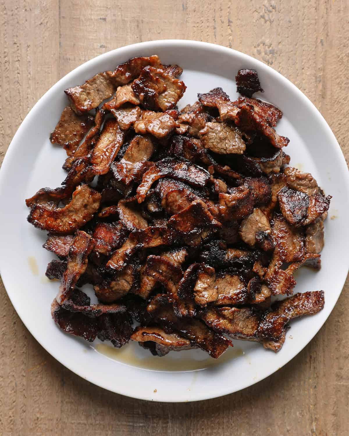 Seared sliced beef transferred to a plate after browning.