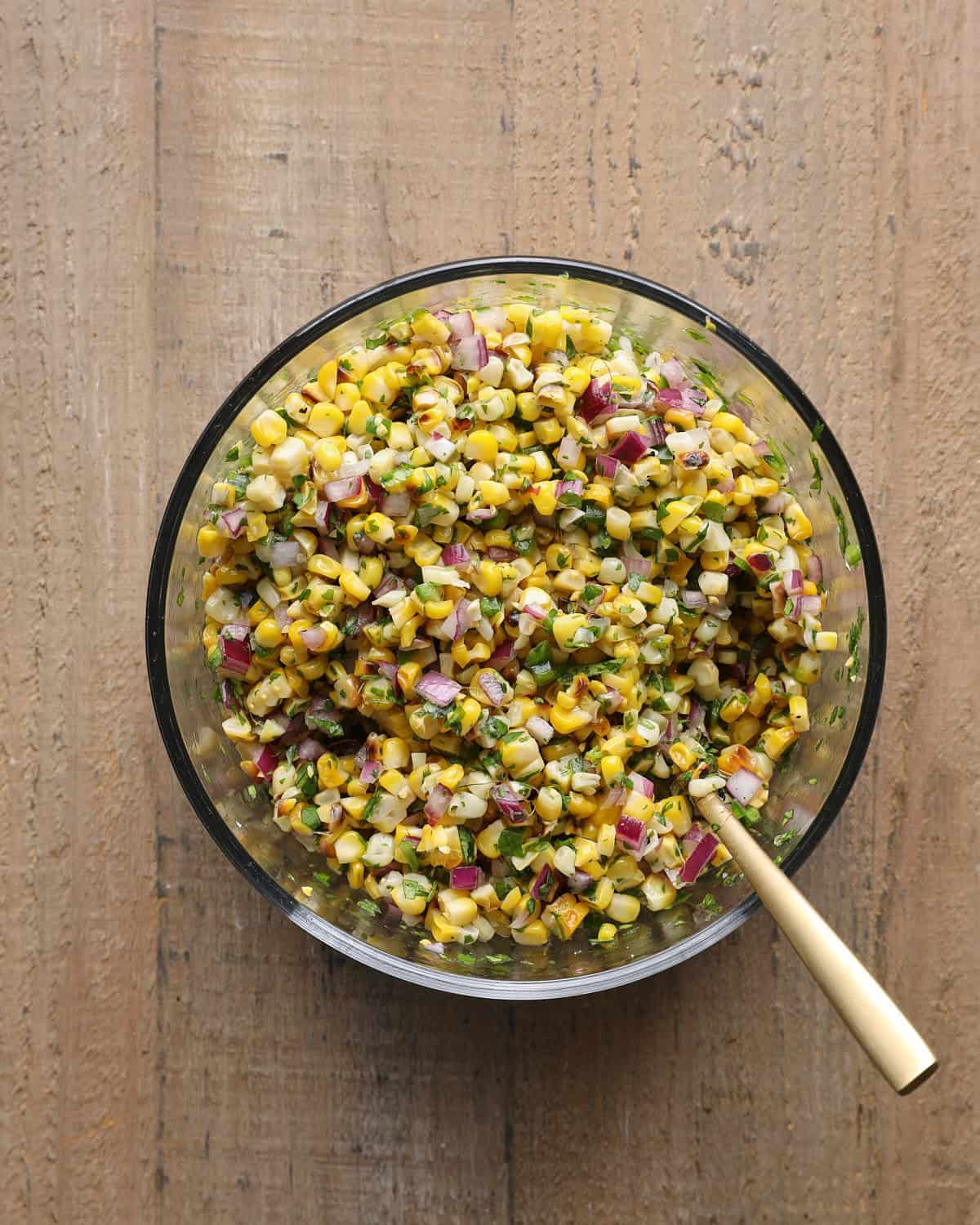 Corn salsa mixed with charred corn, jalapeño, red onion, cilantro, lime juice, and salt.