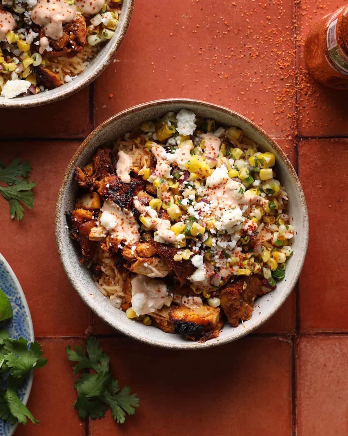 Street corn chicken rice bowl topped with sliced chicken, corn salsa, chipotle crema, Cotija cheese, and Tajín.